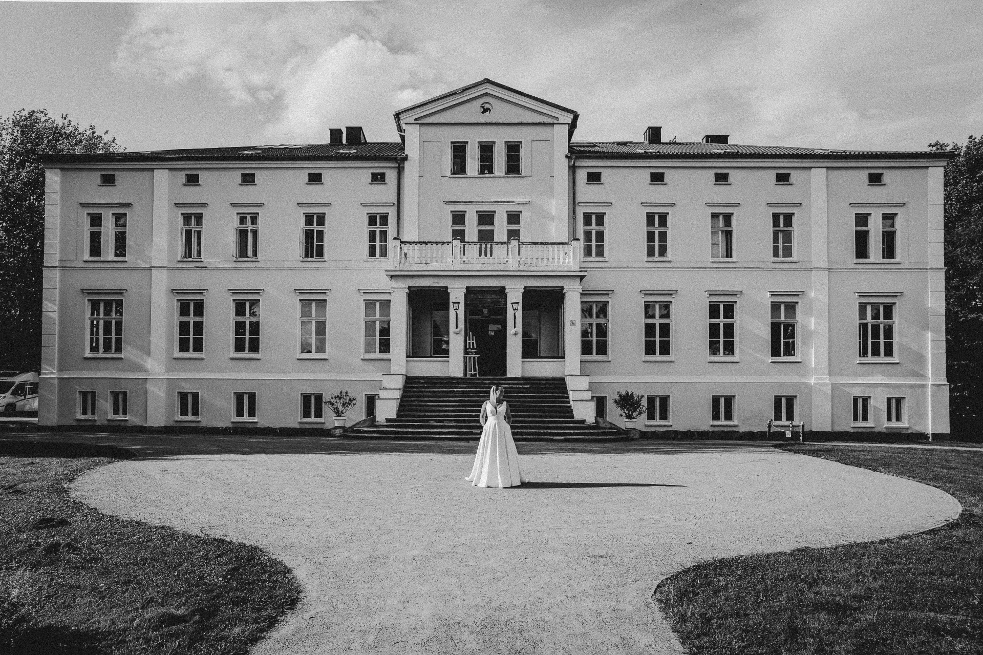 Wedding Planner Hamburg — Braut vor einem norddeutschen Herrenhaus, editorial in Schwarzweiß